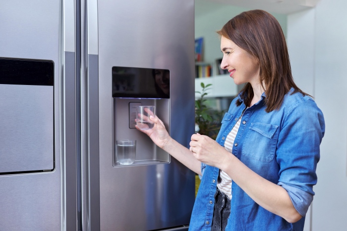 woman beside refrigerator with water dispenser